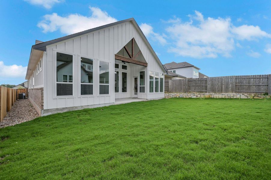 Rear view of house with board and batten siding, ceiling fan, a patio, and a fenced backyard