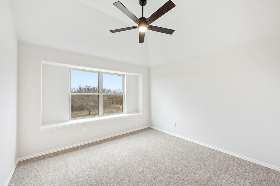 Empty bedroom with carpet flooring, ceiling fan, and large window with outdoor view