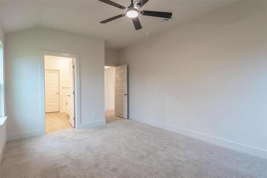 Unfurnished bedroom with light colored carpet, a ceiling fan, and connected bathroom