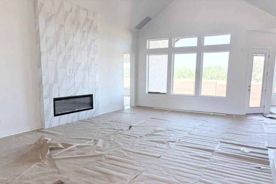 Unfurnished living room featuring high vaulted ceiling and a fireplace