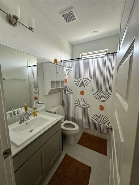 Full bathroom with vanity, toilet, tile patterned flooring, and a shower with curtain