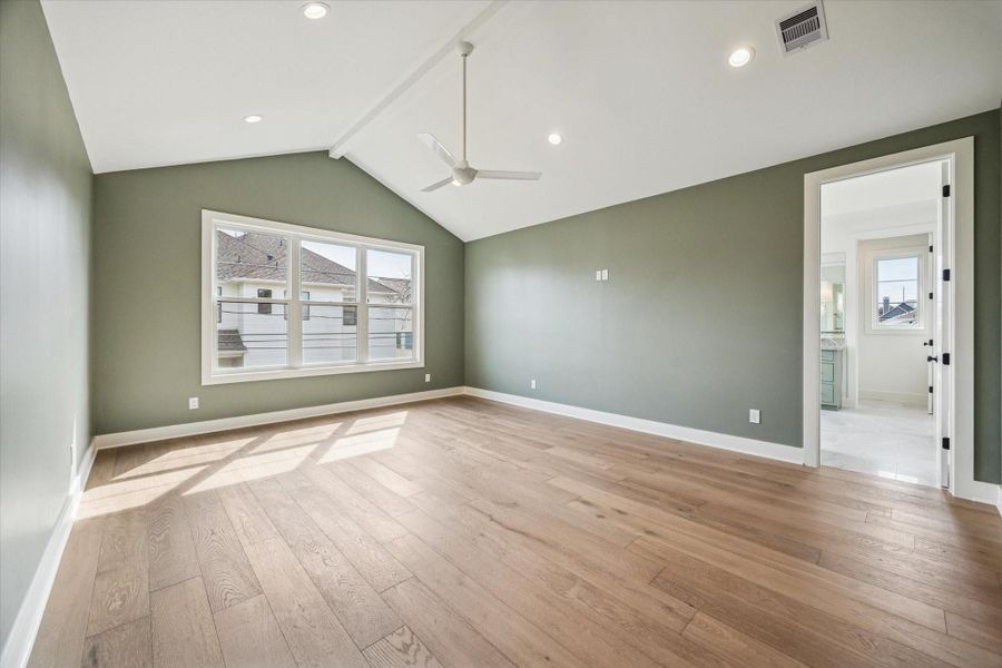 Another perspective of the primary suite highlights the vaulted ceiling line and generous proportions, offering plenty of room for a seating area or king sized layout. Direct access to the spa inspired bath creates a seamless, private retreat feel.