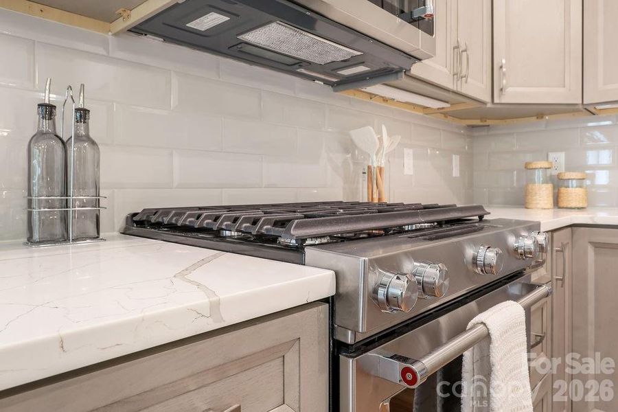 Subway tile backsplash, quartz countertops and gas range.