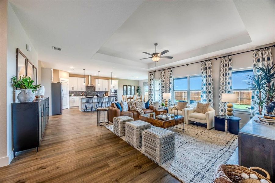 Living room featuring a tray ceiling, light hardwood / wood-style flooring, and ceiling fan