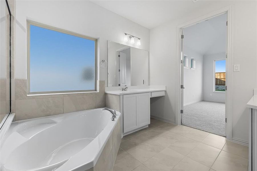 Bathroom featuring vanity, a bath, and light tile patterned floors Bathroom featuring vanity, a bath, and light tile patterned floors