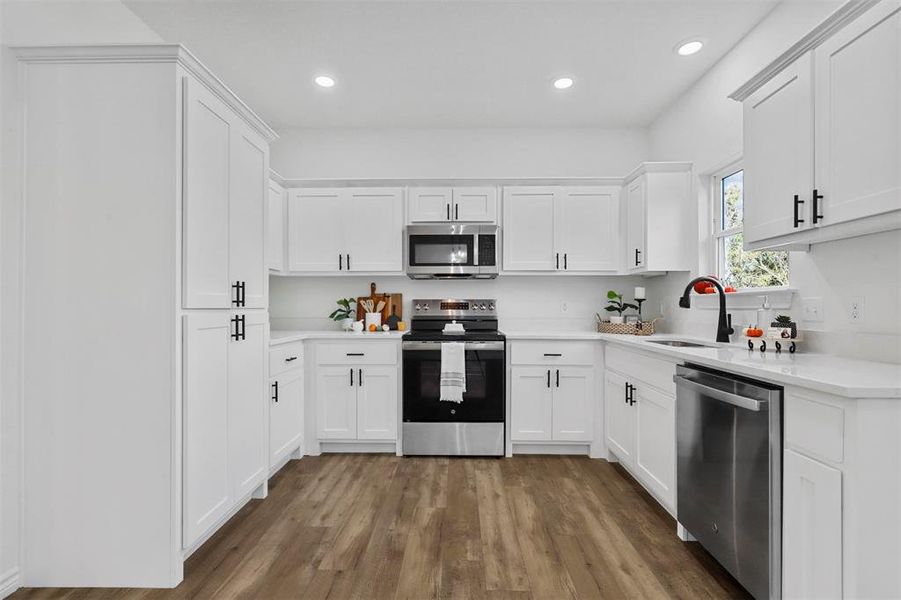 Kitchen featuring appliances with stainless steel finishes, white cabinetry, sink, and dark wood-type flooring