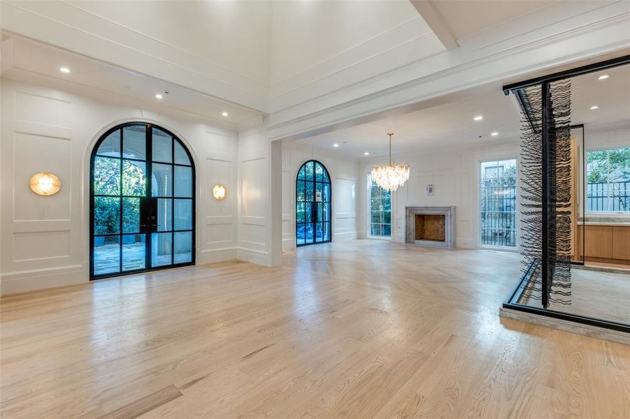 Unfurnished living room with a wealth of natural light, light hardwood / wood-style flooring, and a notable chandelier