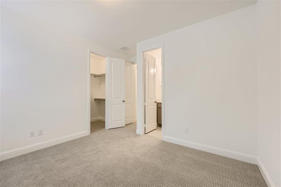 Unfurnished bedroom with light carpet, a closet, and a spacious closet