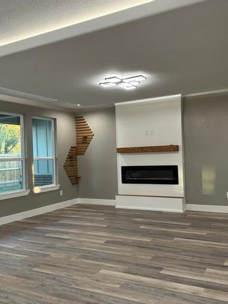 Unfurnished living room with a textured ceiling, a fireplace, and dark wood-type flooring