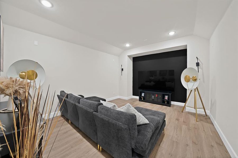 Recessed media wall with a contrasting dark accent, wood-finish flooring, and recessed ceiling lighting Recessed media wall with a contrasting dark accent, wood-finish flooring, and recessed ceiling lighting