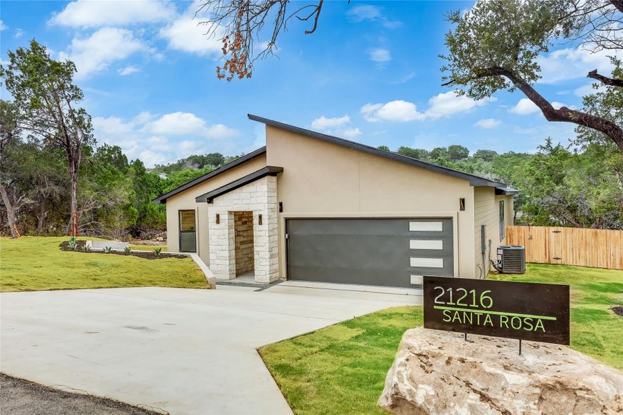View of front facade featuring stone siding, concrete driveway, and stucco siding View of front facade featuring stone siding, concrete driveway, and stucco siding