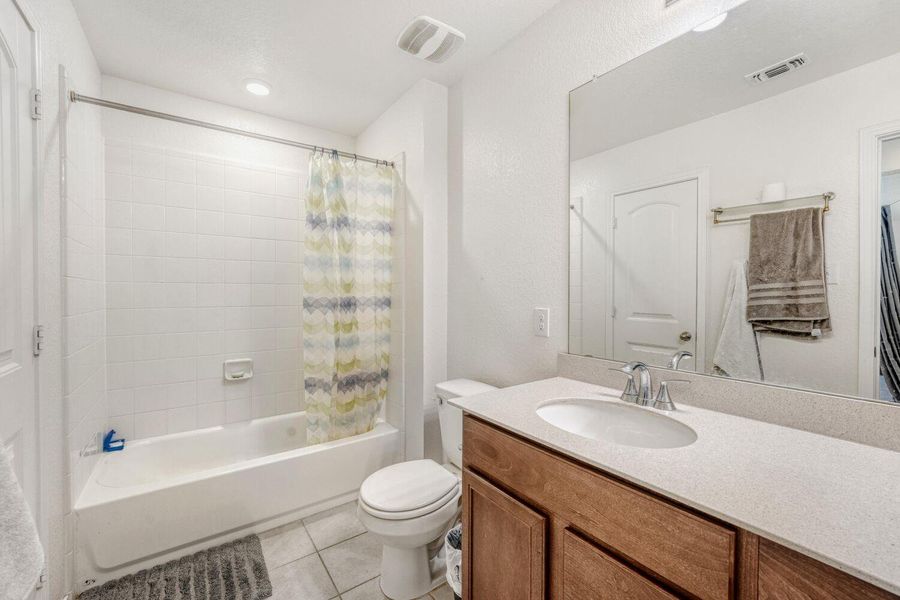 Bathroom with vanity, shower / bath combo, and light tile patterned flooring