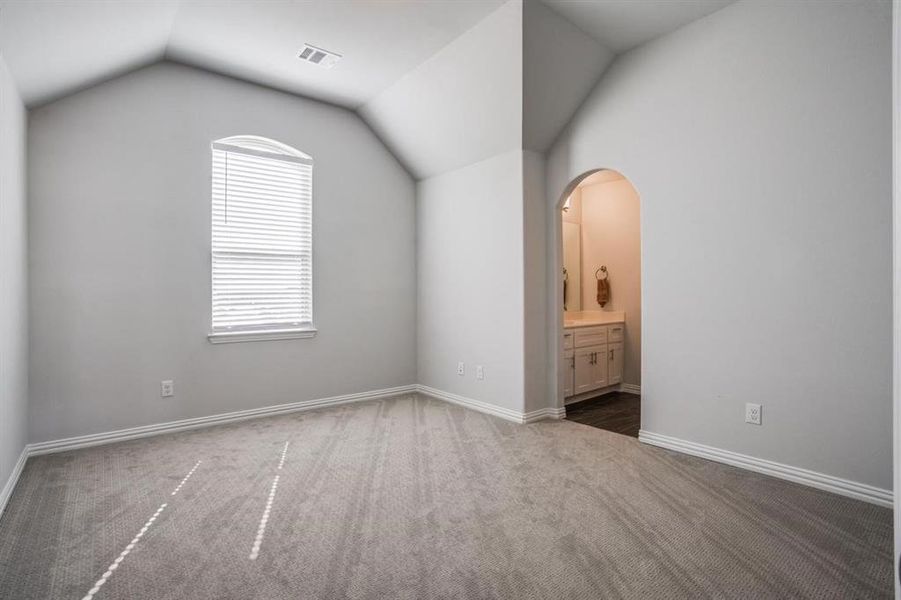 Additional living space with vaulted ceiling and dark colored carpet