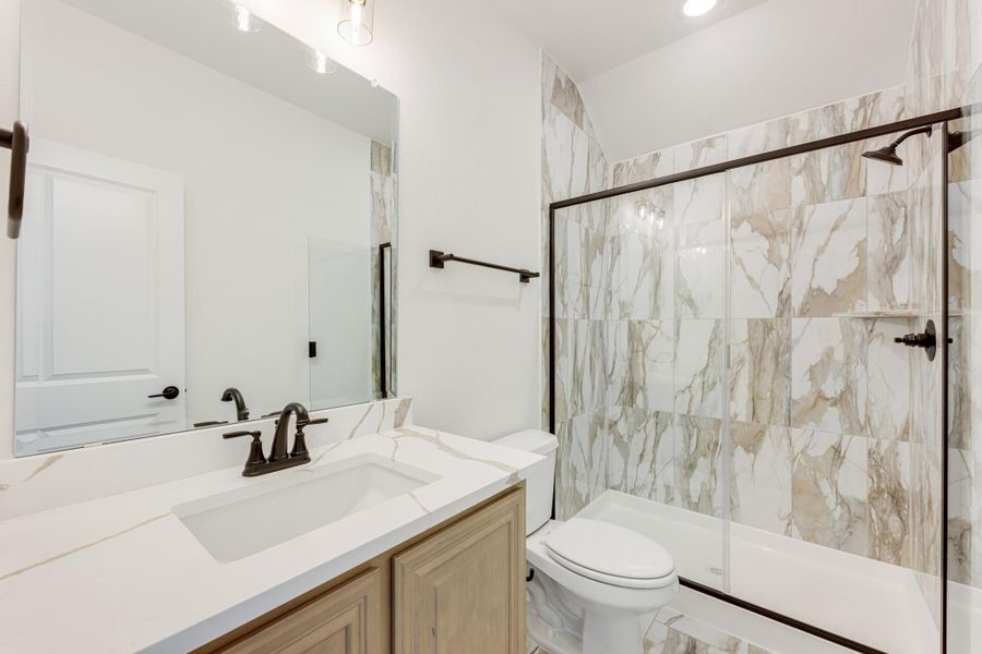 Bathroom with marble-look tile shower, white quartz vanity, wood cabinets, and dark bronze fixtures Bathroom with marble-look tile shower, white quartz vanity, wood cabinets, and dark bronze fixtures