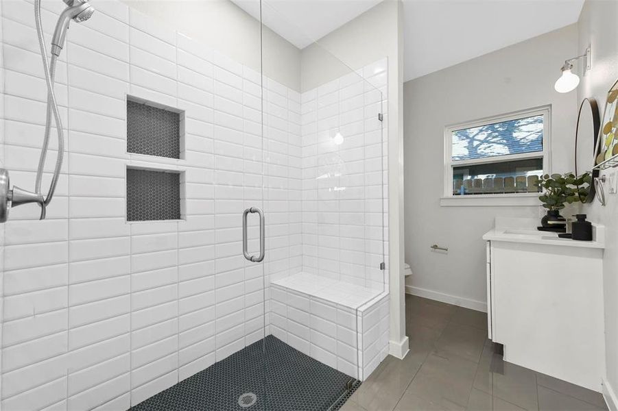 Bathroom featuring walk in shower, tile patterned floors, vanity, and toilet