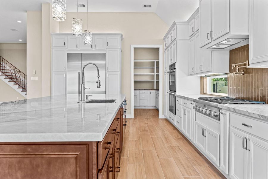 Alternate angle highlighting the custom cabinetry, tile backsplash, and seamless flow into adjoining living spaces.