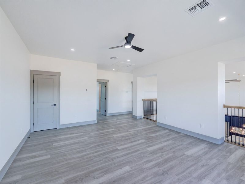 Smooth wood-look flooring and crisp white walls define this open upper-level landing space.