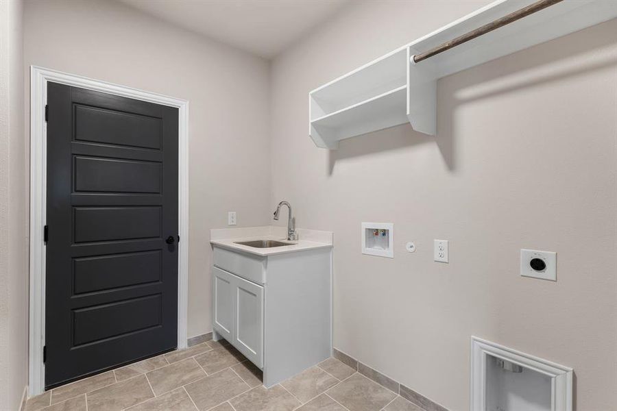 Washroom with gas dryer hookup, sink, electric dryer hookup, hookup for a washing machine, and light tile patterned floors