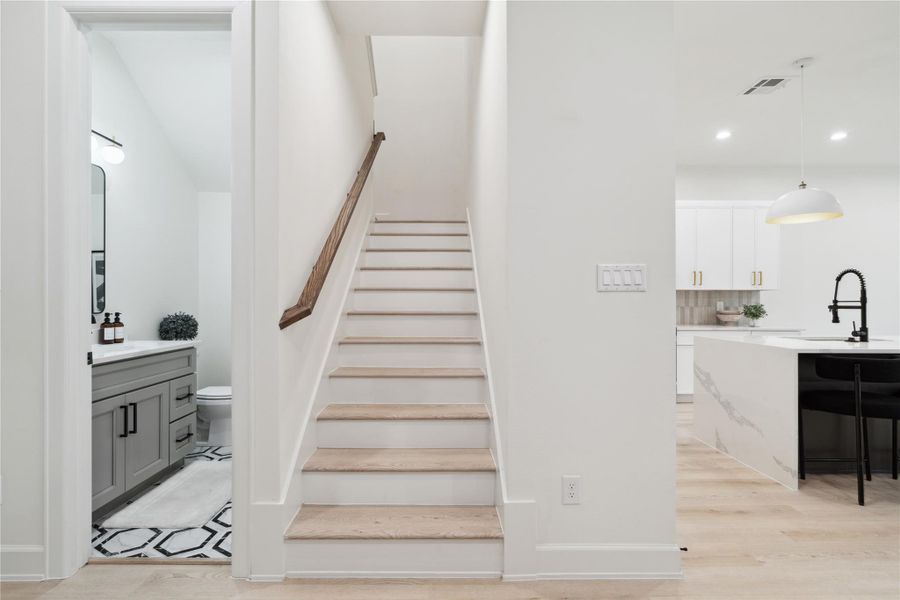 A sleek and space-efficient half bath conveniently tucked under the staircase, featuring modern finishes and designer touches.