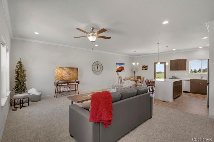 Living room with recessed lighting, ornamental molding, a ceiling fan, and carpeting