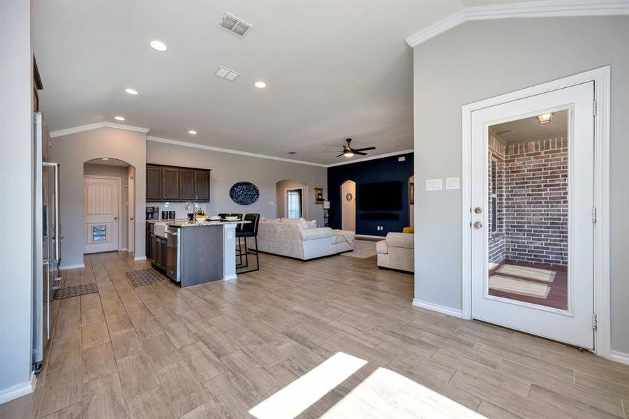 Living room with arched walkways, crown molding, ceiling fan, wood finish floors, and recessed lighting