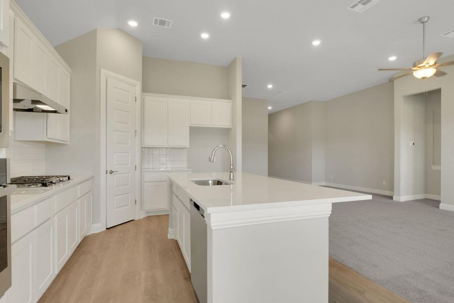 Kitchen featuring a ceiling fan, visible vents, appliances with stainless steel finishes, a sink, and backsplash