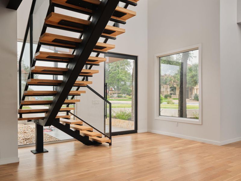 Natural light floods this inviting entryway, highlighting the elegant hardwood floors and modern floating staircase. Natural light floods this inviting entryway, highlighting the elegant hardwood floors and modern floating staircase.