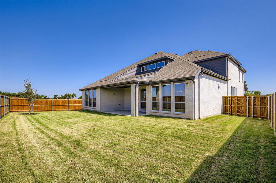 Rear view of house with brick siding, a fenced backyard, a shingled roof, and a patio area