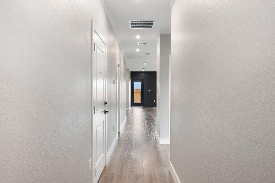 Hallway featuring a textured wall and light wood-style floors