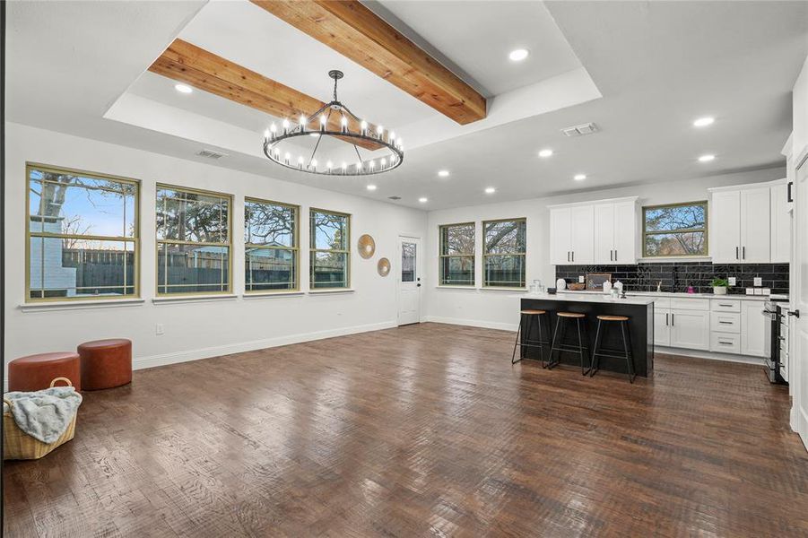 Kitchen with open floor plan, white cabinetry, beamed ceiling, a breakfast bar, and a center island with sink