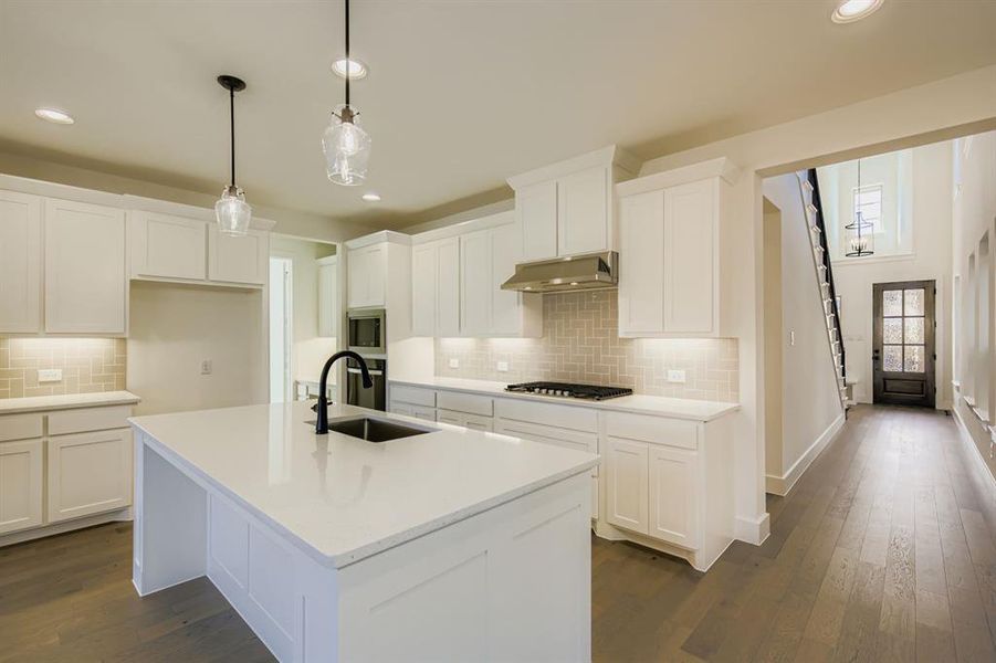 Kitchen featuring hanging light fixtures, white cabinets, dark wood-type flooring, and recessed lighting Kitchen featuring hanging light fixtures, white cabinets, dark wood-type flooring, and recessed lighting