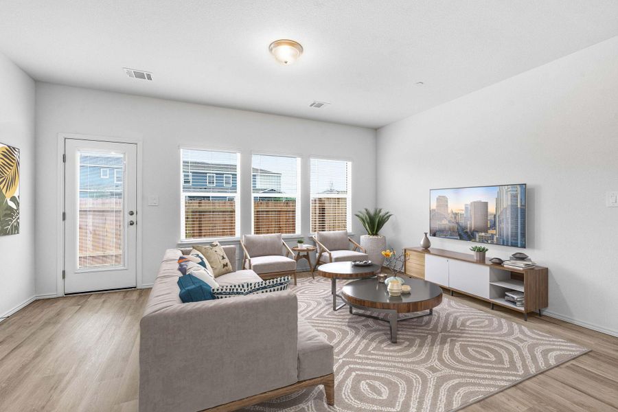 Spacious living area featuring light wood-finish flooring, white walls, and a ceiling light fixture