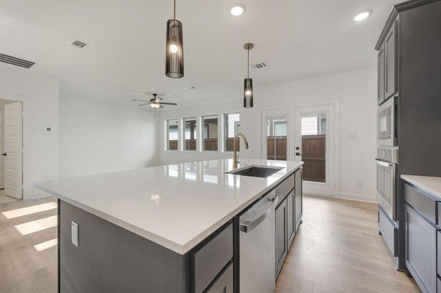Kitchen island with a white solid surface countertop and undermount sink, complemented by dual pendant lighting fixtures