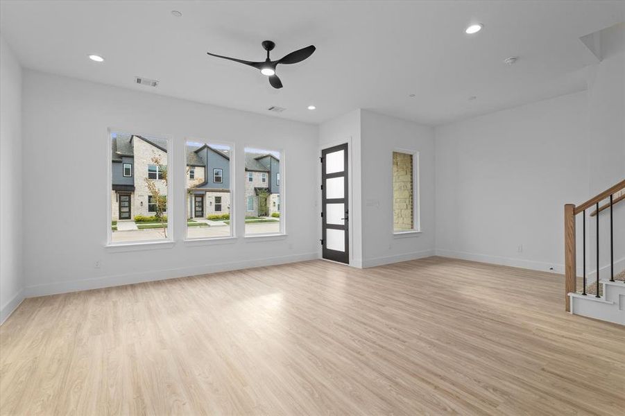 Unfurnished living room featuring light wood finished floors, recessed lighting, a ceiling fan, and stairs Unfurnished living room featuring light wood finished floors, recessed lighting, a ceiling fan, and stairs