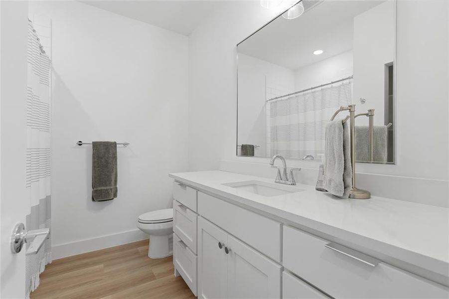 Bathroom featuring a single vanity with a white countertop, built-in cabinetry, and a large wall-mounted mirror