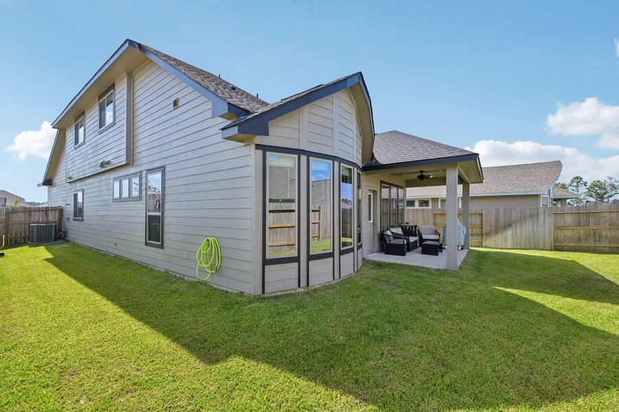Spacious backyard with lush grass and a cozy covered patio, perfect for outdoor relaxation and entertaining.