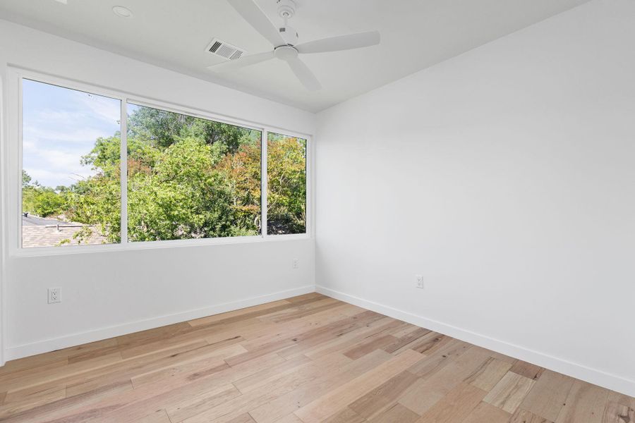Empty room featuring baseboards, light wood-style flooring, and ceiling fan