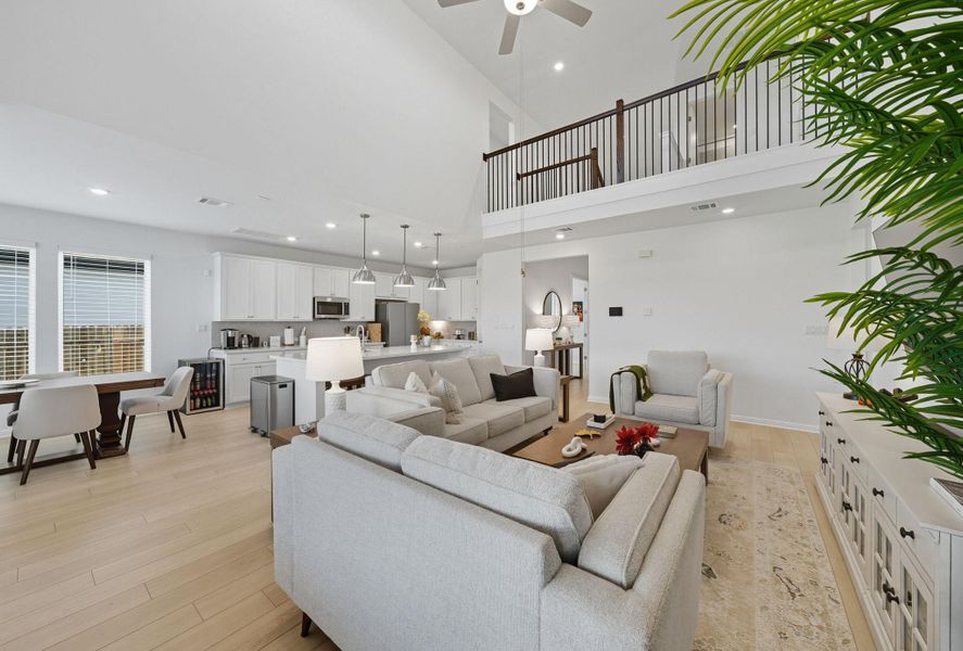 Living area with light wood finished floors, recessed lighting, ceiling fan, and a high ceiling Living area with light wood finished floors, recessed lighting, ceiling fan, and a high ceiling