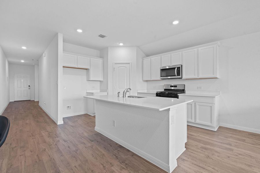 Kitchen featuring white cabinets, recessed lighting, appliances with stainless steel finishes, light wood-style floors, and a kitchen island with sink Kitchen featuring white cabinets, recessed lighting, appliances with stainless steel finishes, light wood-style floors, and a kitchen island with sink