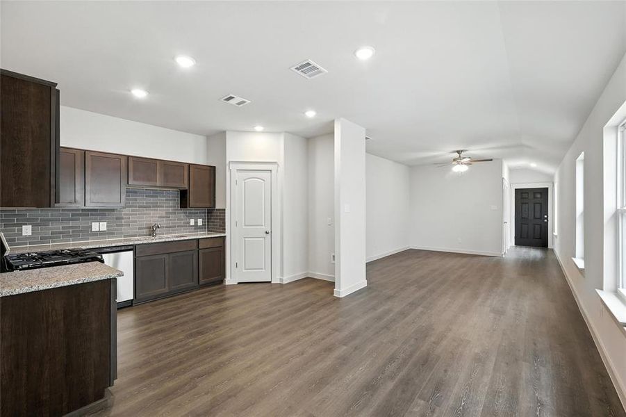 Kitchen with backsplash, ceiling fan, dark brown cabinets, dark wood-style floors, and stainless steel dishwasher Kitchen with backsplash, ceiling fan, dark brown cabinets, dark wood-style floors, and stainless steel dishwasher