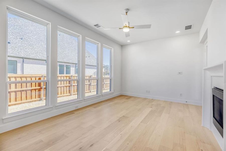 Unfurnished living room with ceiling fan, light wood-style floors, a fireplace, and recessed lighting