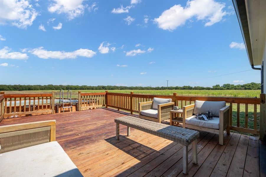 Backyard wooden deck lounging area featuring a view of open pastures Backyard wooden deck lounging area featuring a view of open pastures