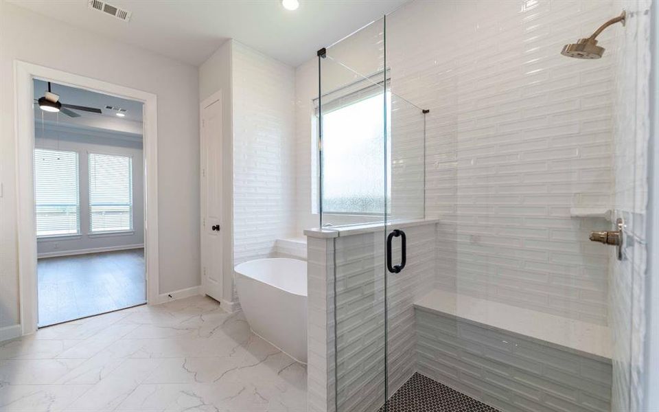 Contemporary bathroom featuring a freestanding tub, glass-enclosed shower with integrated bench, and wall-mounted shower head Contemporary bathroom featuring a freestanding tub, glass-enclosed shower with integrated bench, and wall-mounted shower head