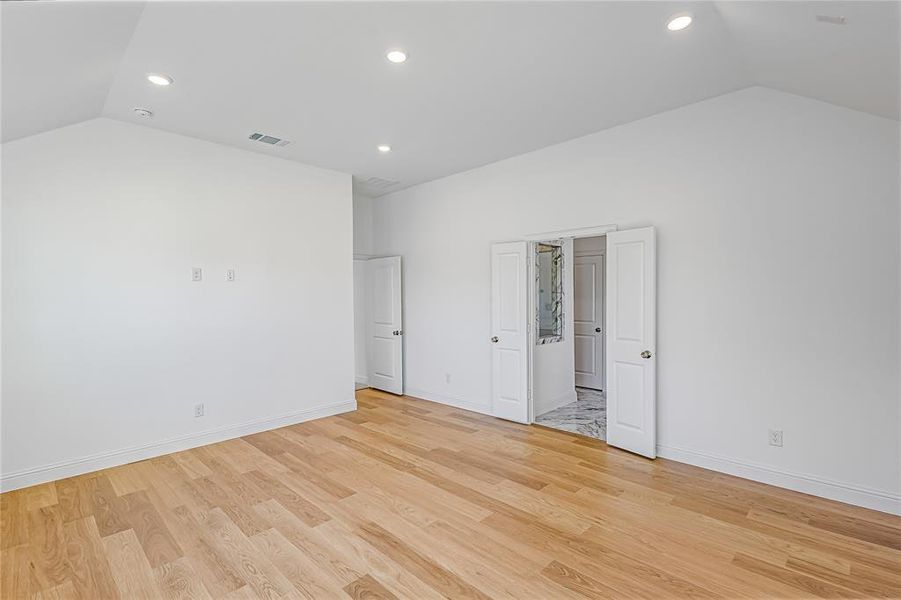 Spare room with vaulted ceiling and light hardwood / wood-style flooring