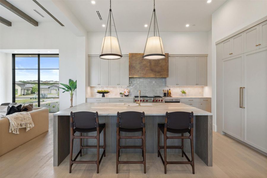 Kitchen with decorative backsplash, visible vents, light wood-style floors, and a spacious island Kitchen with decorative backsplash, visible vents, light wood-style floors, and a spacious island