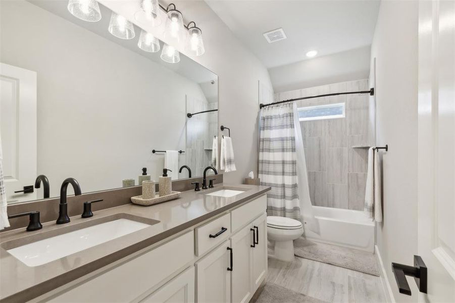 Full bathroom featuring vanity, shower / bath combination with curtain, and toilet