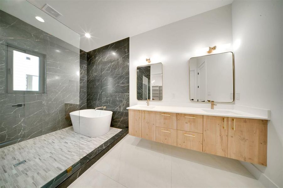 Bathroom with tile patterned flooring, vanity, a tub to relax in, and tile walls