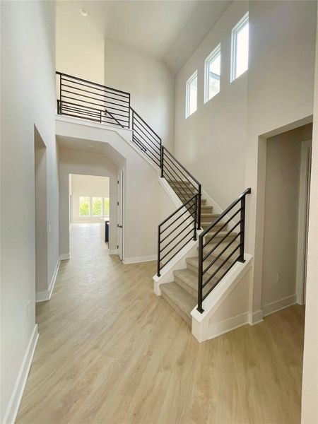 A grand entrance with high ceilings, modern railings, and light wood flooring sets a welcoming tone. A grand entrance with high ceilings, modern railings, and light wood flooring sets a welcoming tone.