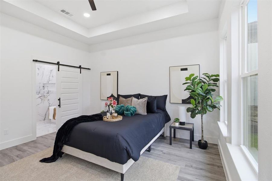 Spacious room featuring a tray ceiling, recessed lighting, and wood-finish flooring