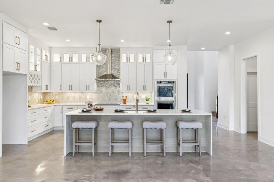 The chef's kitchen is anchored by a massive Luce Oro quartz waterfall island. High-end design meets functionality with soft-close custom cabinetry.